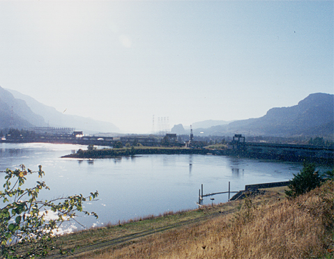 long dam crossing the river with a monolithic rock far in the background