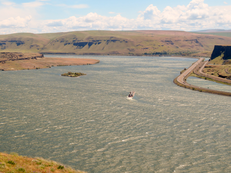 A tug pushes a barge between Miller Island and the mouth of the Deschutes