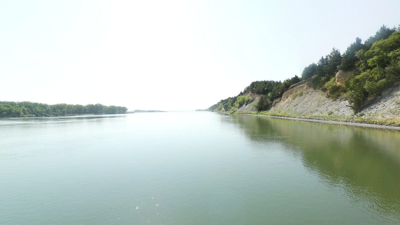 The Missouri River below a steep, eroded bluff with scattered trees on the right, 2021