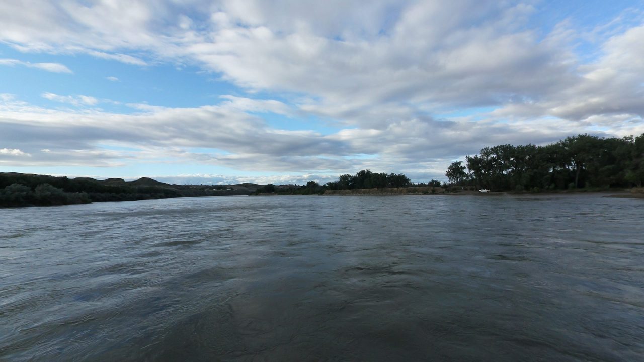 The Yellowstone River under layered clouds, with cottonwoods on the right bank, 2024