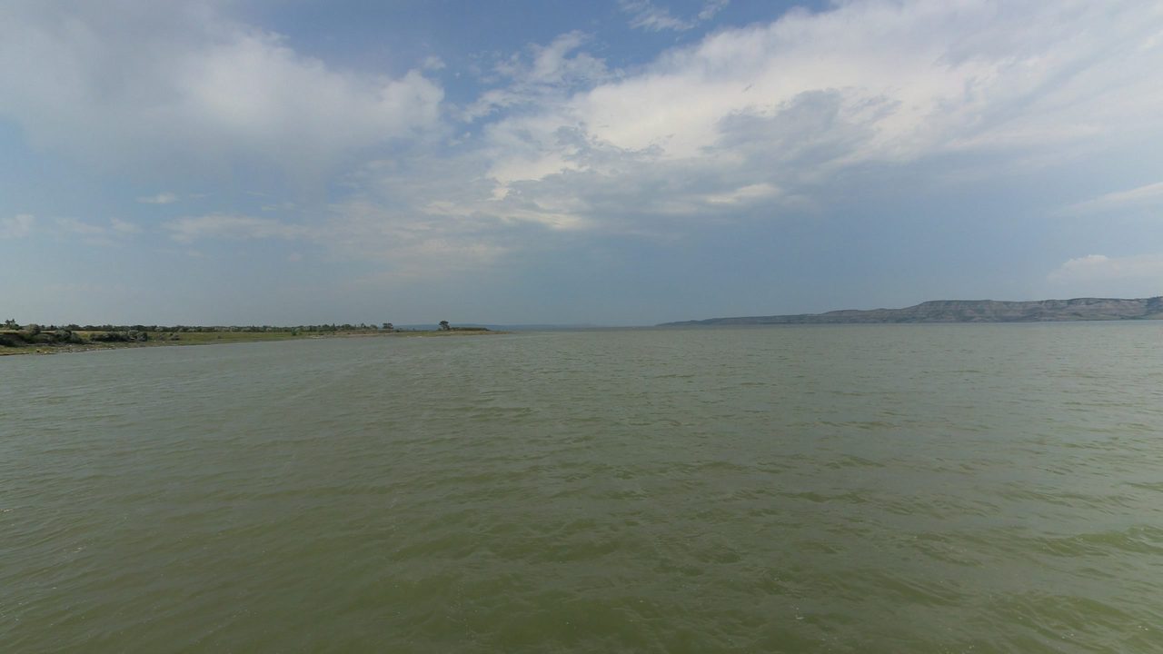 The wide Missouri River under a sky of layered clouds, with low shores in the distance, 2024