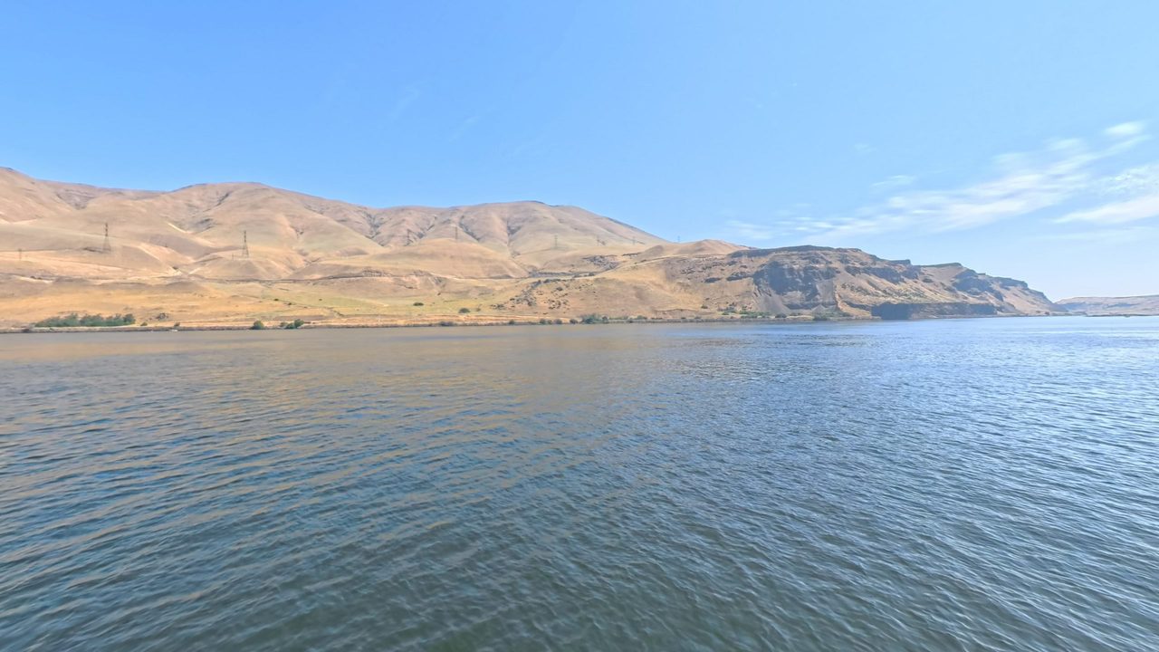 The Columbia River below dry, grassy hills and dark basalt cliffs, 2025