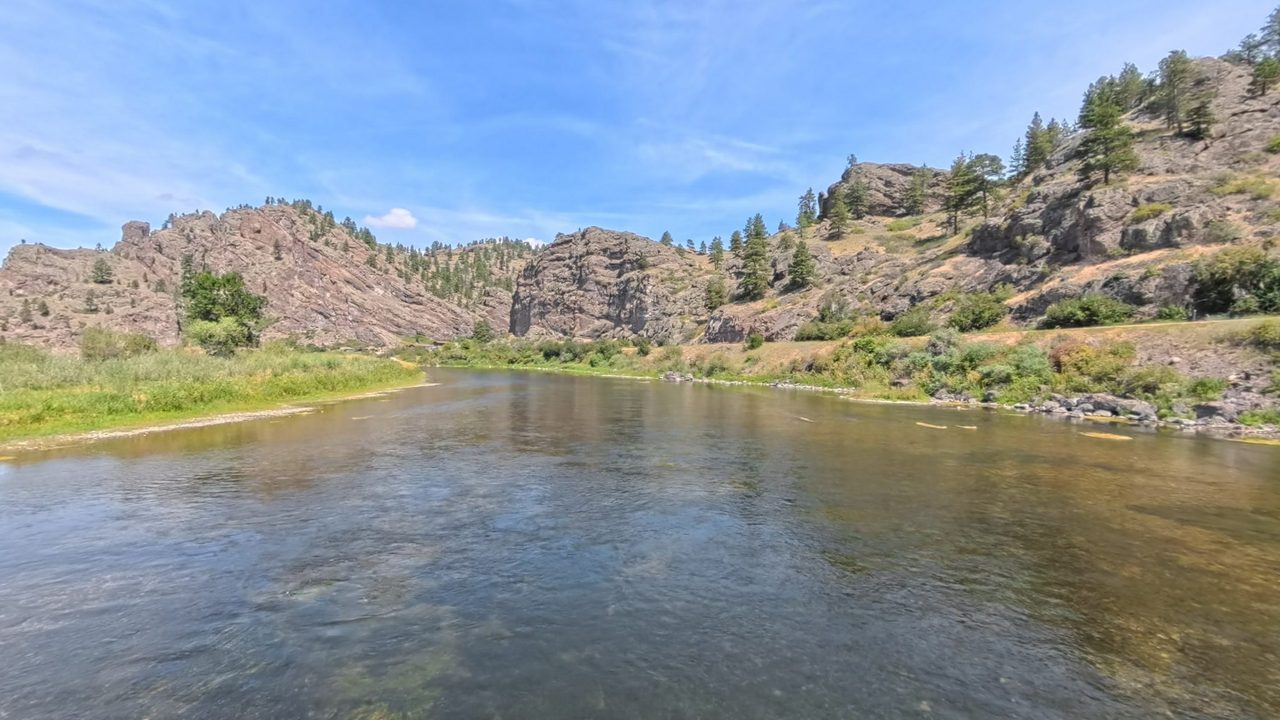 The clear, shallow Missouri River below rugged rock outcrops and scattered pines, 2025