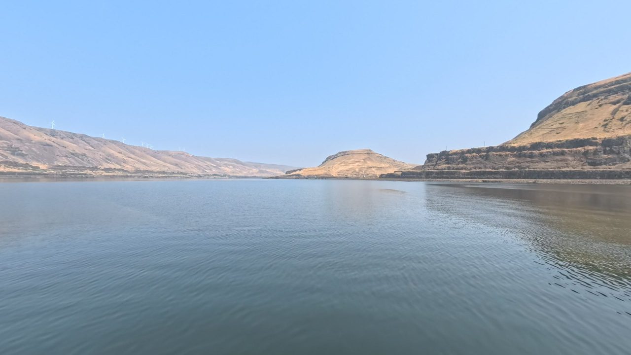 The Columbia River between dry, golden hills and basalt bluffs under a clear sky, 2025