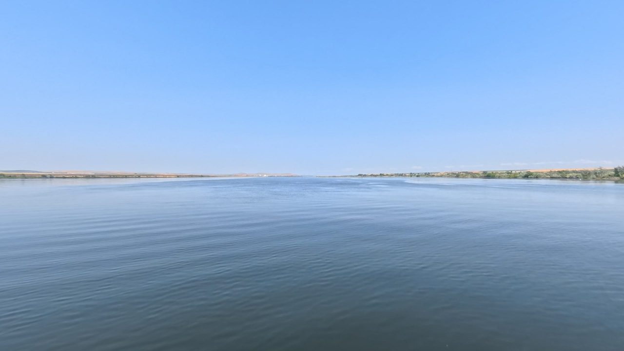 The wide, calm Columbia River under a clear blue sky, with low, distant shores, 2025