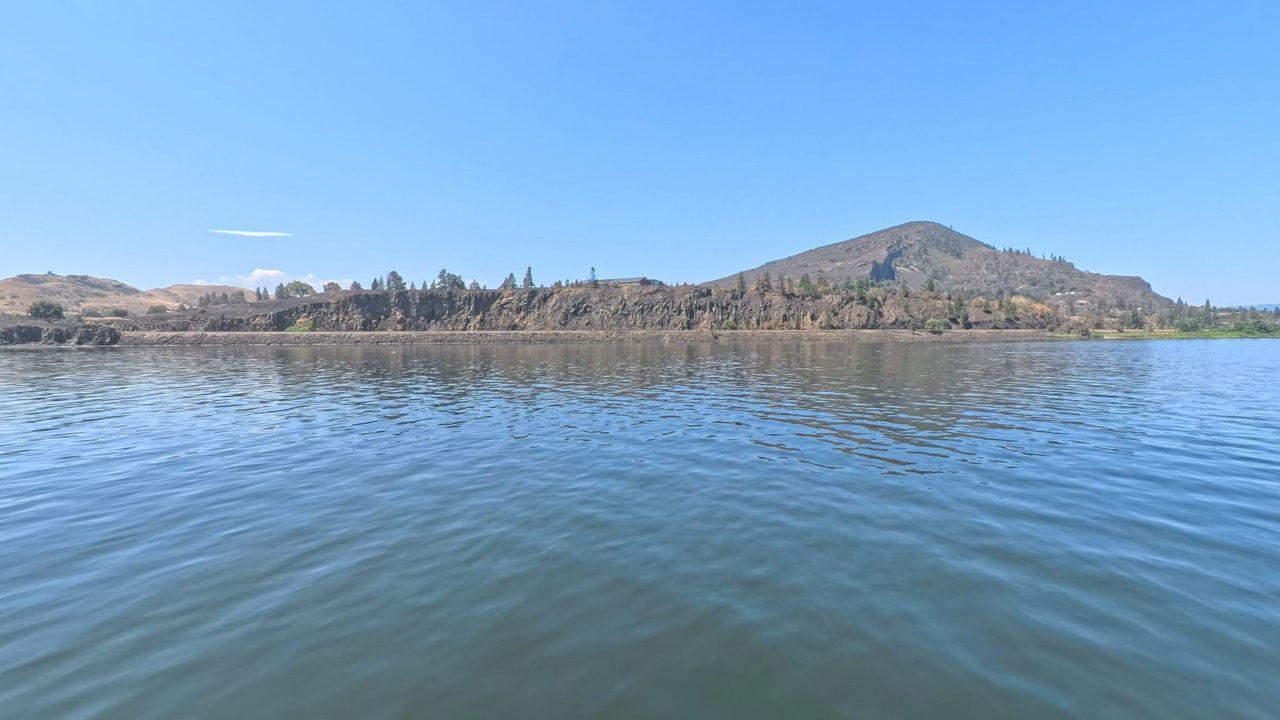 Dark basalt cliffs topped with pines above the rippling Columbia River, 2025
