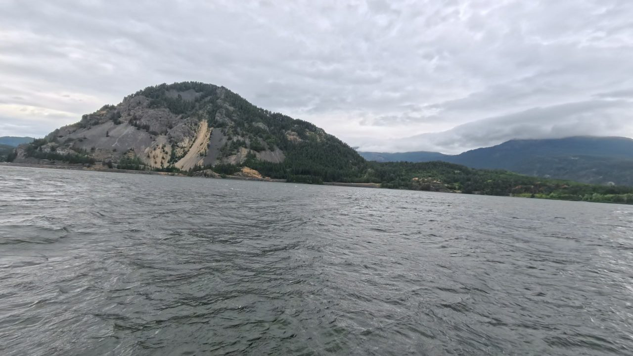 The Columbia River below the steep, rocky dome of a mountain, under a cloudy sky, 2025