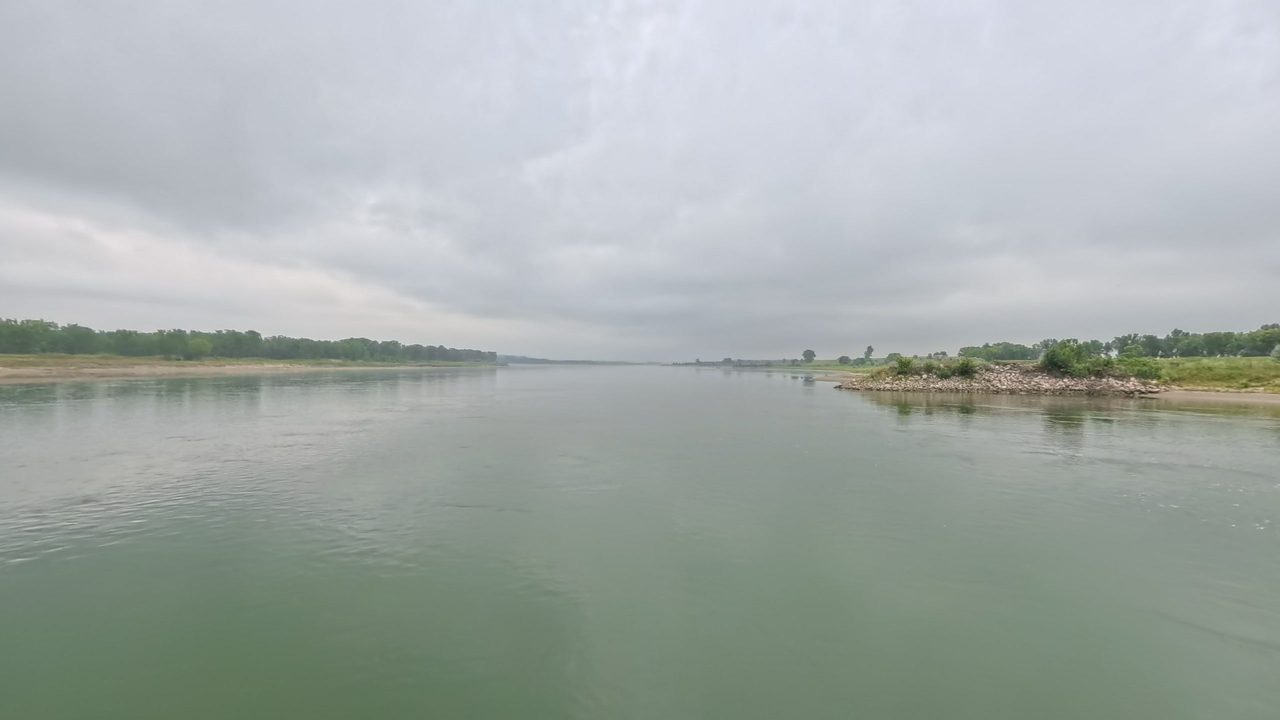 The wide Missouri River between low, distant shores under a heavy grey sky, 2025