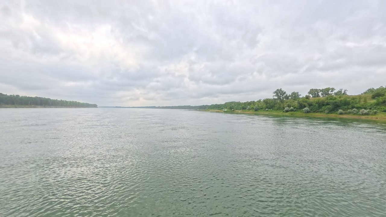 The Missouri River beside a wooded bank on the right, under a cloudy sky, 2025