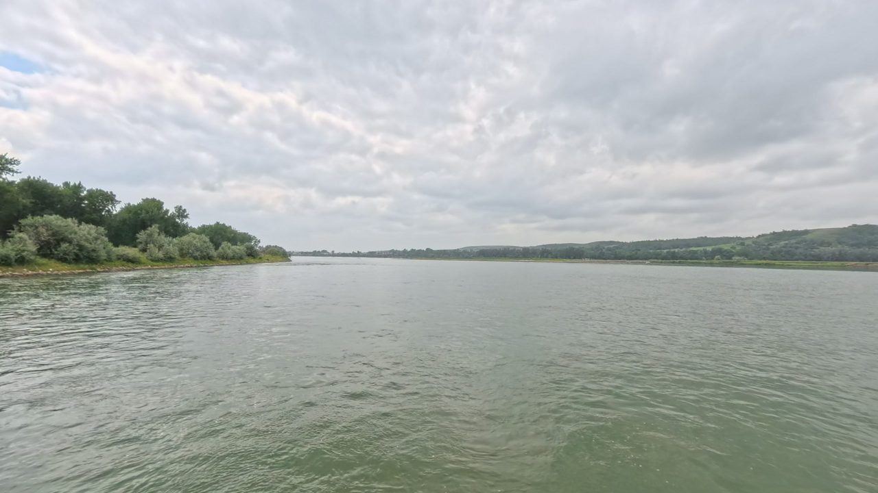 The Missouri River with a wooded point on the left and low hills across the water, 2025