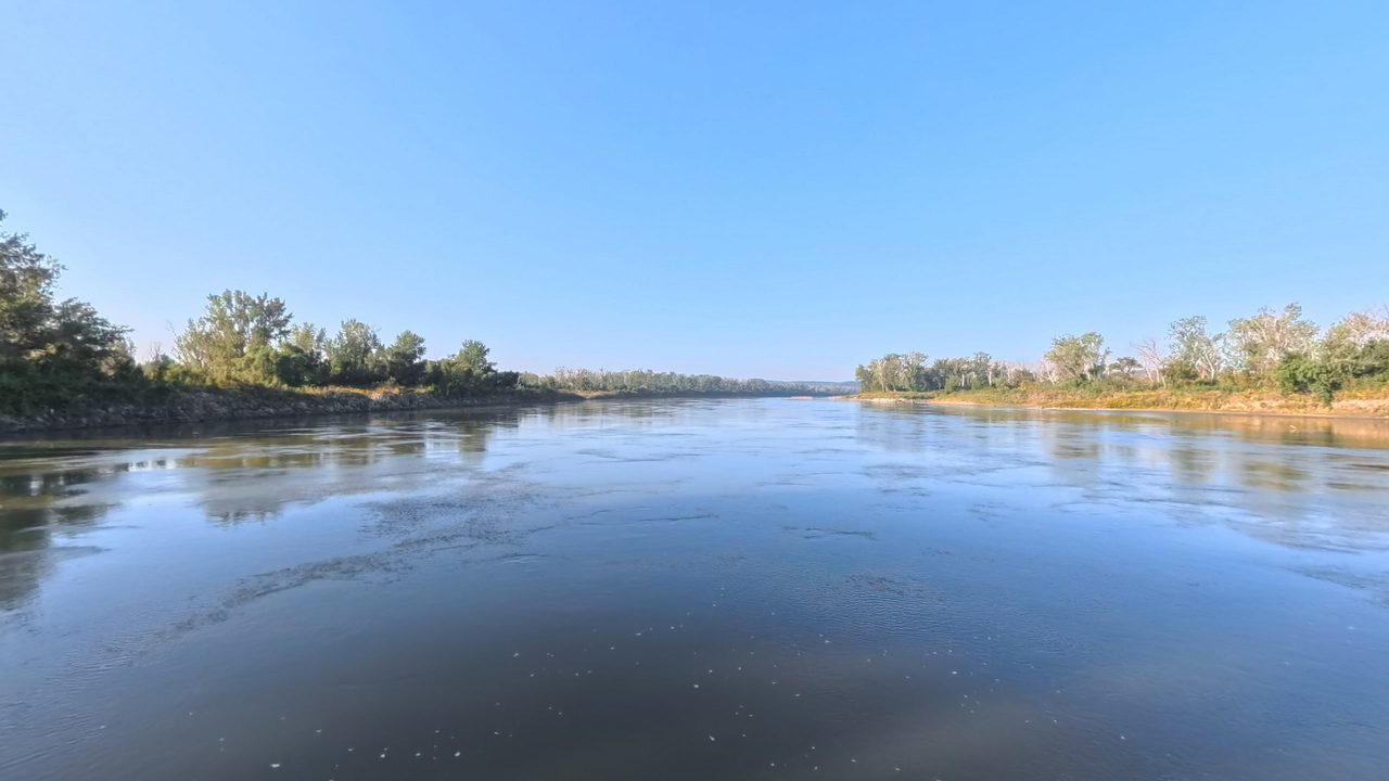 The Missouri River curving between leafy banks under a clear blue sky, 2025