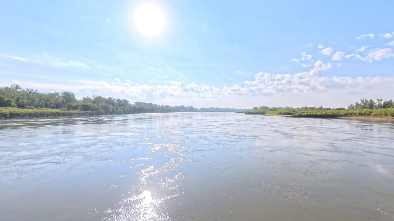 Sunlight glittering on the Missouri River between green banks, 2025