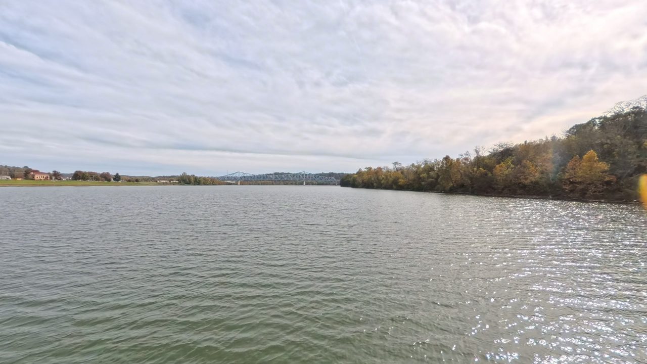 The Ohio River with glinting water and wooded hills in autumn color on the right, 2025