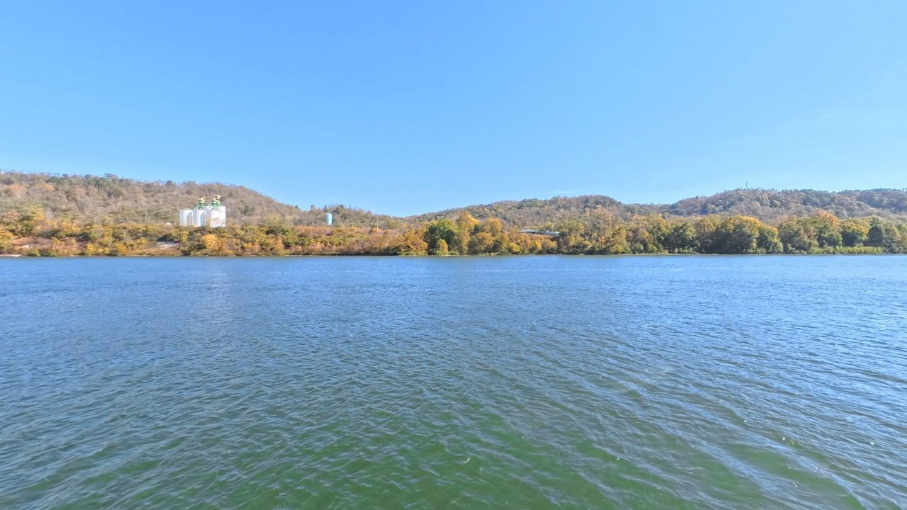 Autumn woods along the Ohio River, with white storage tanks on a wooded hillside, 2025
