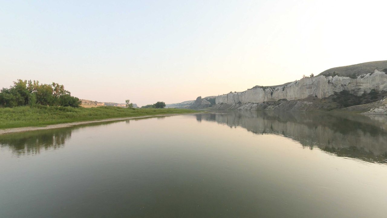 White sandstone cliffs reflected in the calm Missouri River, 2021