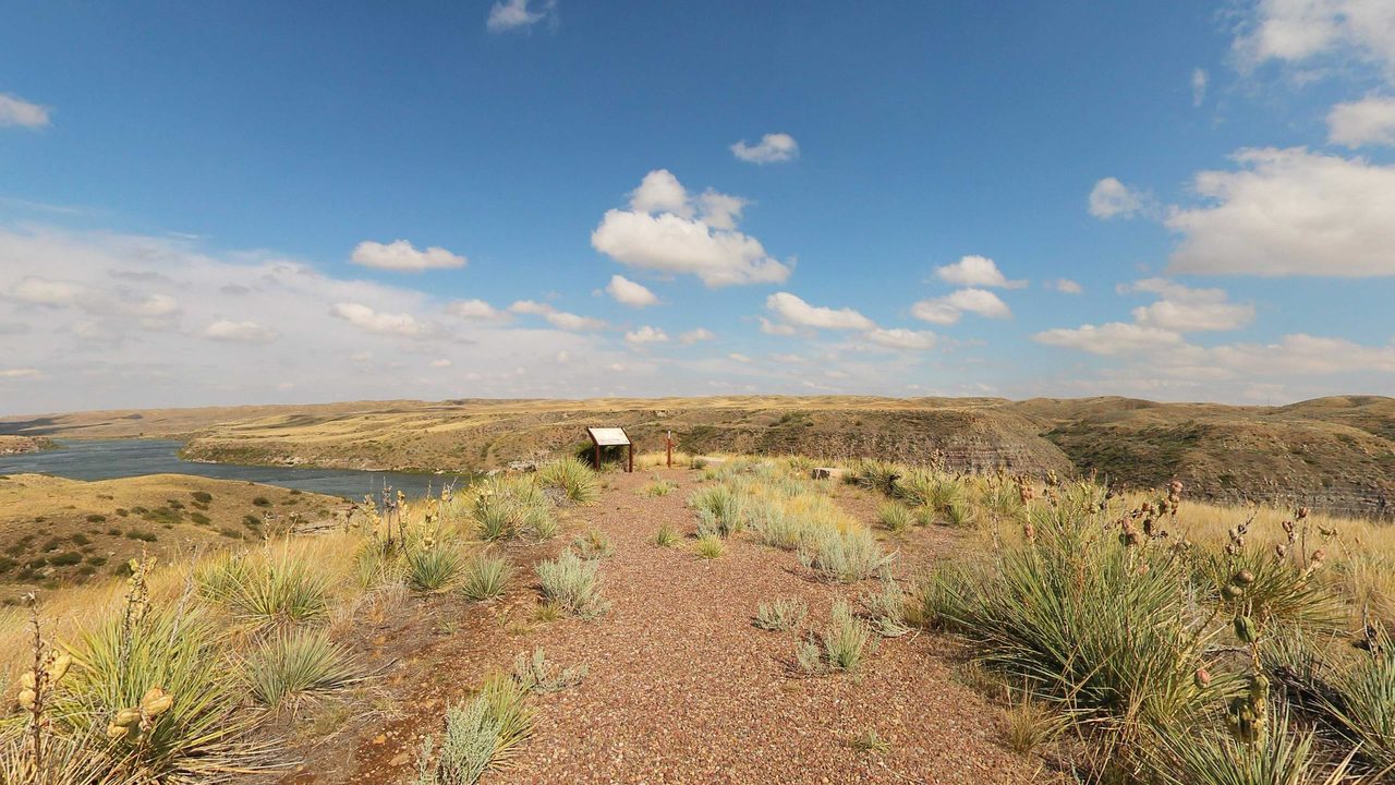 A gravel overlook path through yucca and dry grass above the Missouri River, with layered bluffs beyond, 2022