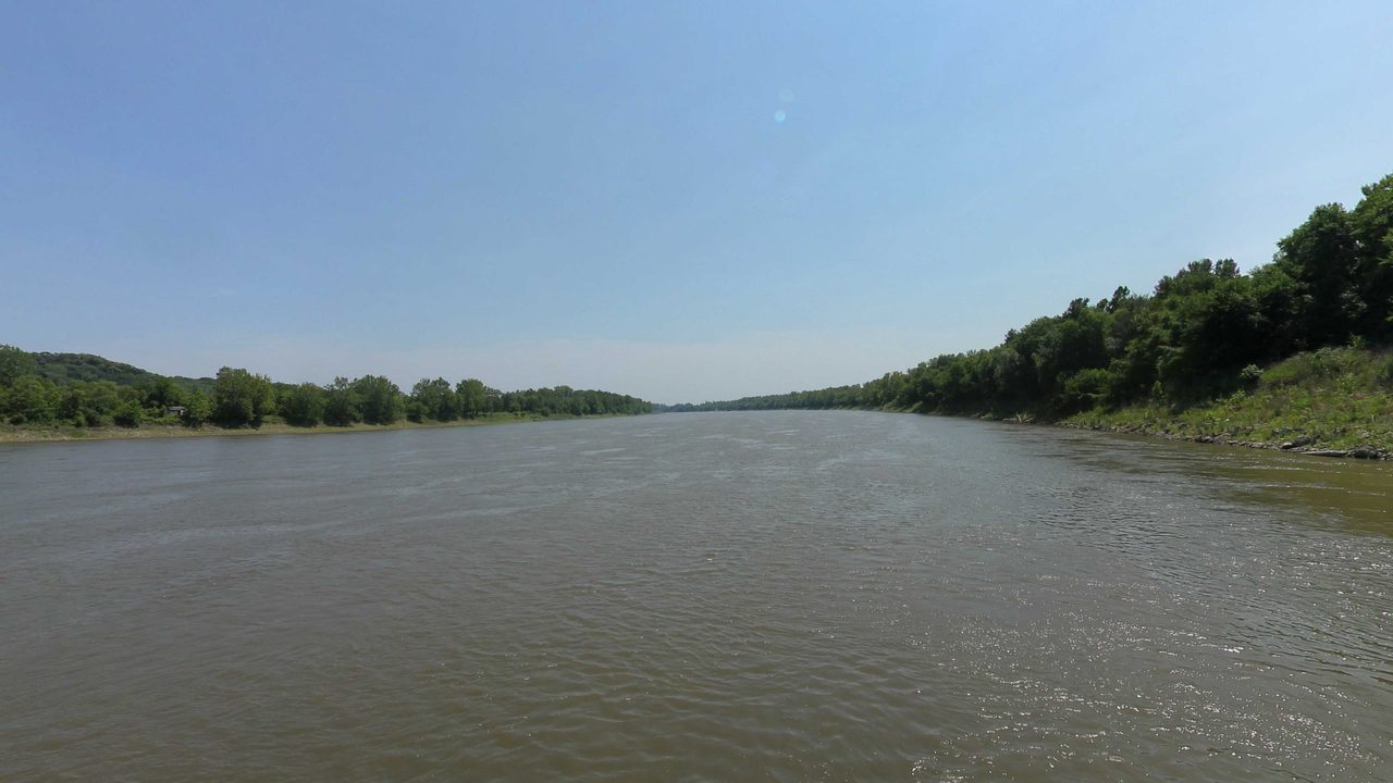 The Missouri River between wooded banks under a clear sky, 2023