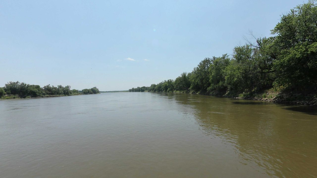The broad Missouri River with a tree-lined bank on the right, 2023