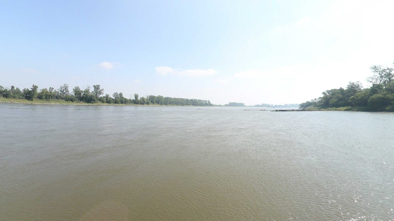 The Missouri River between low wooded banks, with a wooded point on the right, 2023
