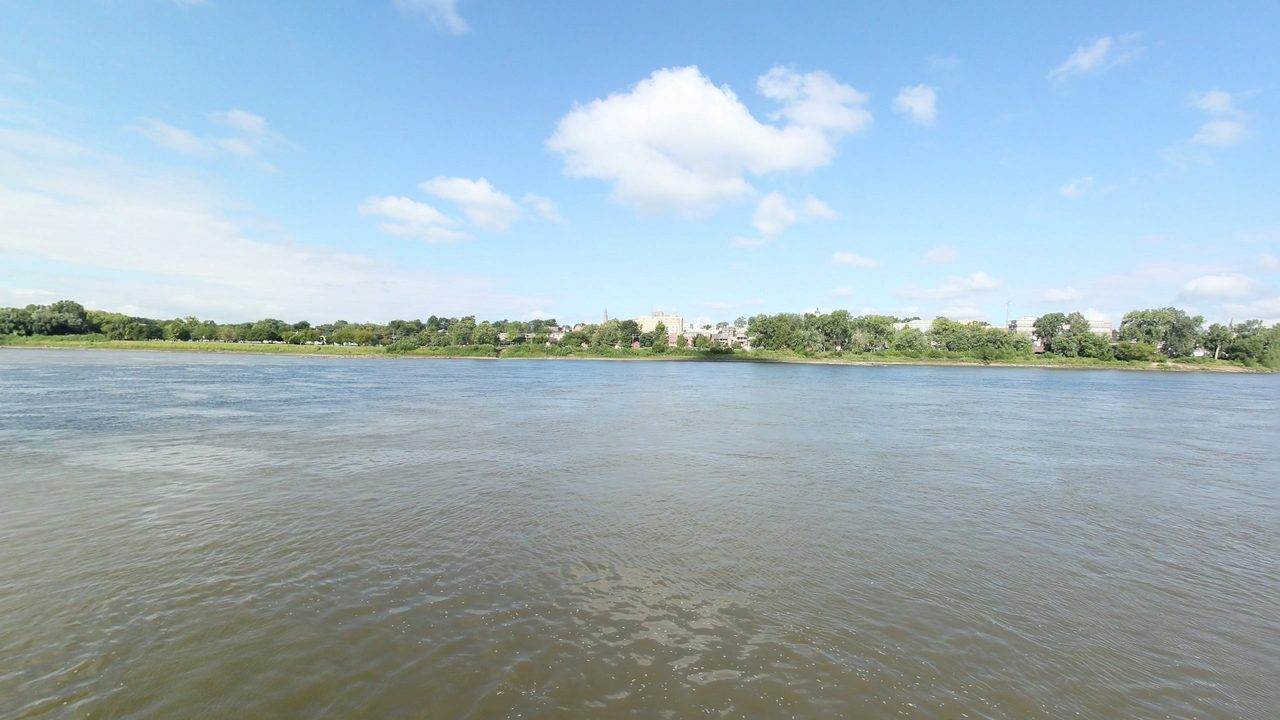 The Missouri River with a riverside town of brick buildings and a church spire on the far bank, 2023